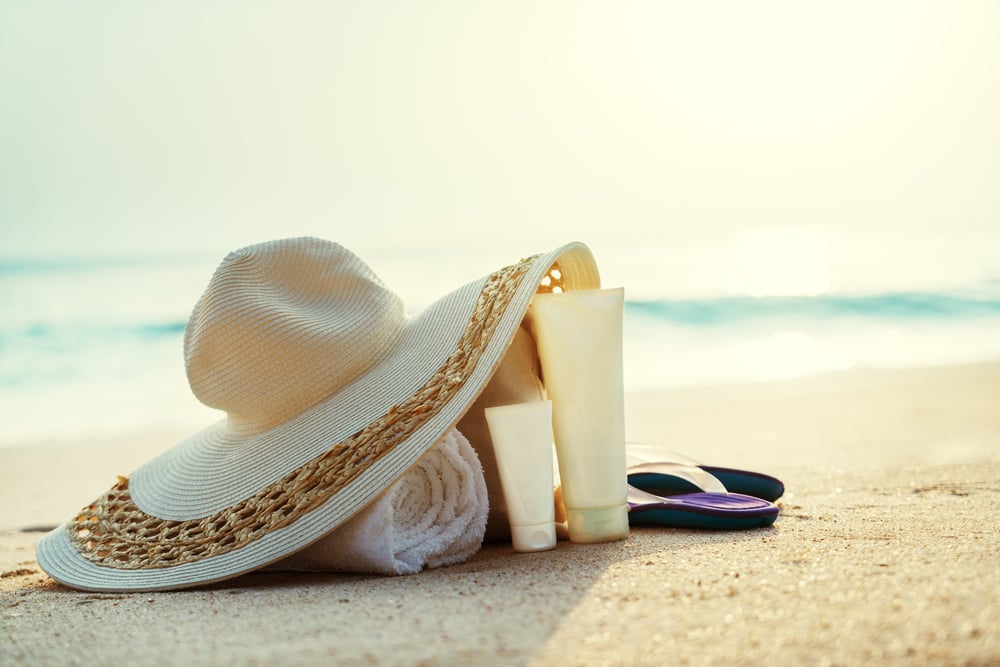 Sun lotion, hat with bag at the tropical beach 